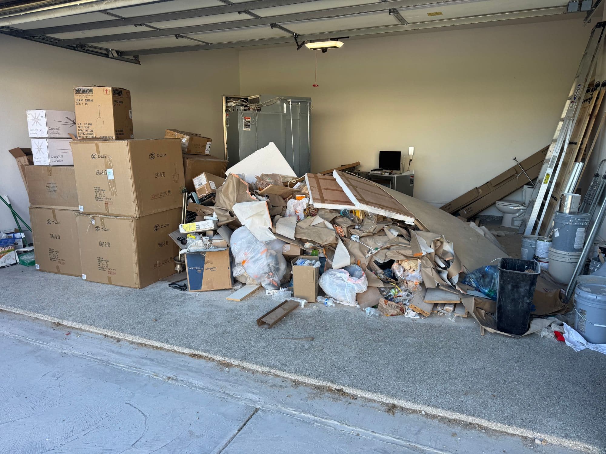 Garage full of construction debris, cardboard, and junk before HAULR removal